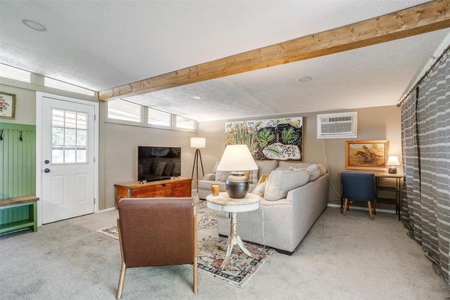 Carpeted living room with a wall mounted air conditioner and beamed ceiling | Image 23