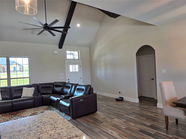 Living room with dark wood finished floors, arched walkways, ceiling fan, beam ceiling, and high vaulted ceiling | Image 8