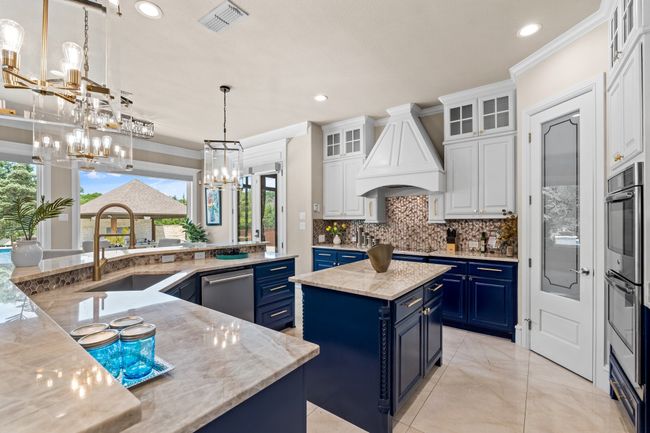 Kitchen featuring blue cabinets, a chandelier, custom range hood, a center island, and recessed lighting | Image 6