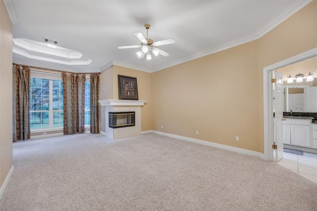 Unfurnished living room featuring crown molding, light colored carpet, a ceiling fan, and a fireplace with flush hearth | Image 21