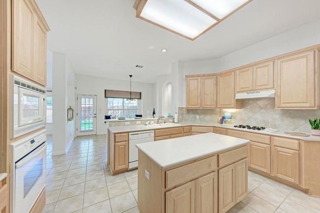 Kitchen with under cabinet range hood, light brown cabinets, and white appliances | Image 17