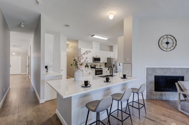 Kitchen featuring appliances with stainless steel finishes, a breakfast bar area, wood finished floors, a sink, and a textured ceiling | Image 18