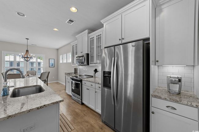 Kitchen featuring appliances with stainless steel finishes, a sink, white cabinets, baseboards, and recessed lighting | Image 5