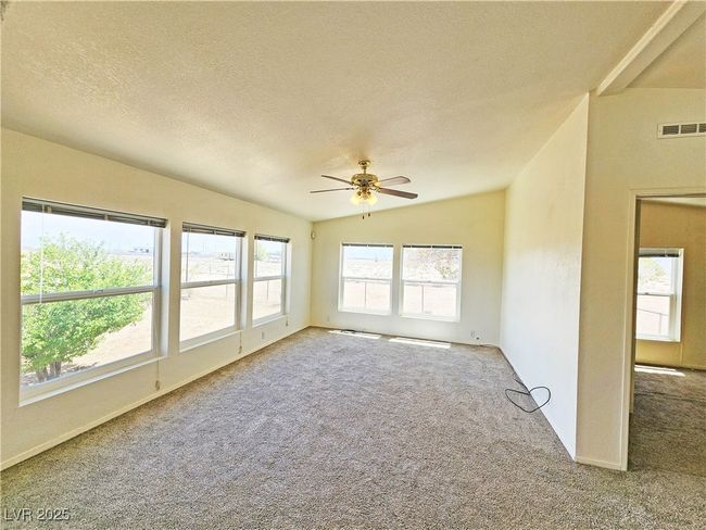 Empty room with carpet flooring, visible vents, ceiling fan, and a healthy amount of sunlight | Image 12