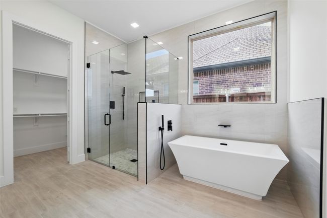 Bathroom featuring a walk in closet, a freestanding tub, tile walls, a shower stall, and wood finished floors | Image 33