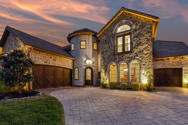 View of front facade featuring decorative driveway, a balcony, stone siding, a tiled roof, and a garage | Image 31