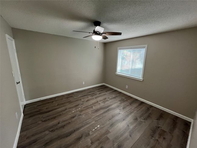 Spare room featuring dark wood-type flooring, ceiling fan, baseboards, and a textured ceiling | Image 11