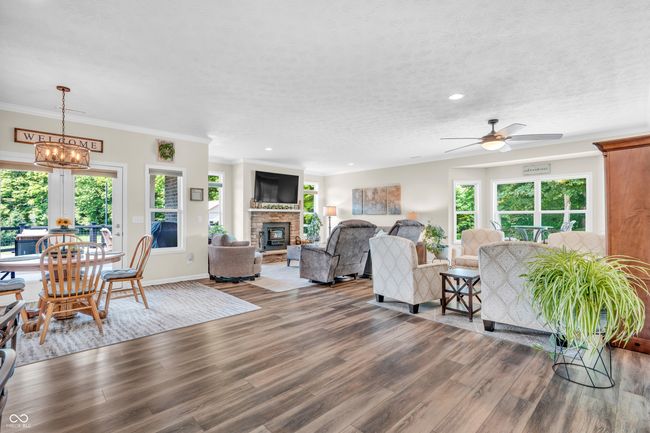 living area featuring plenty of natural light, vinyl plank flooring, a ceiling fan, recessed lighting, wood burning fireplace w/insert & blower | Image 16