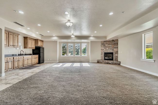 Unfurnished living room featuring recessed lighting, plenty of natural light, light carpet, a fireplace, and a textured ceiling | Image 9