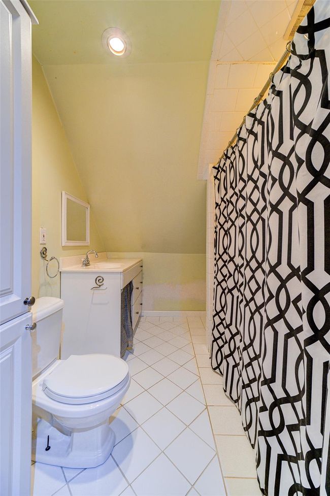 Bathroom with lofted ceiling, tile patterned floors, vanity, and toilet | Image 33