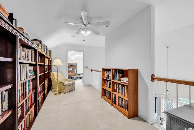 Living area with ceiling fan, carpet floors, lofted ceiling, and wall of books | Image 28