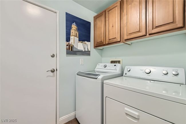 Doorway to 2-car garage by the interior laundry washer & dryer space with overhead cabinets | Image 11