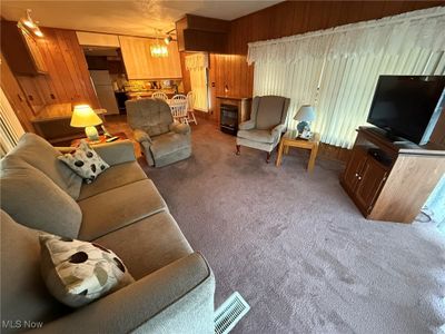 Carpeted living room with wooden walls and a fireplace | Image 2