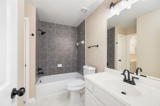 Past an enclosed door, you'll find a tub-shower combo, a toilet, and extra counter space with a separate faucet—all convenient for ease and functionality. | Image 32