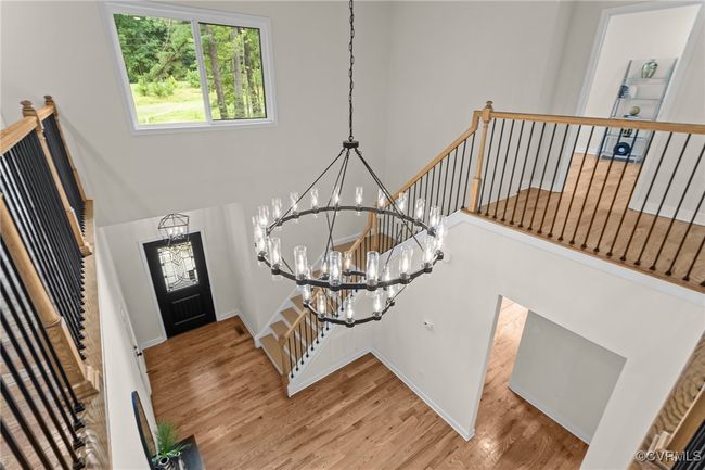 Entrance foyer featuring a chandelier, wood finished floors, a towering ceiling, and stairway | Image 10