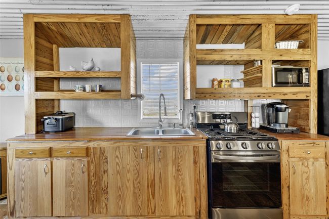 Kitchen featuring tasteful backsplash, open shelves, a sink, butcher block counters, and stainless steel appliances | Image 6