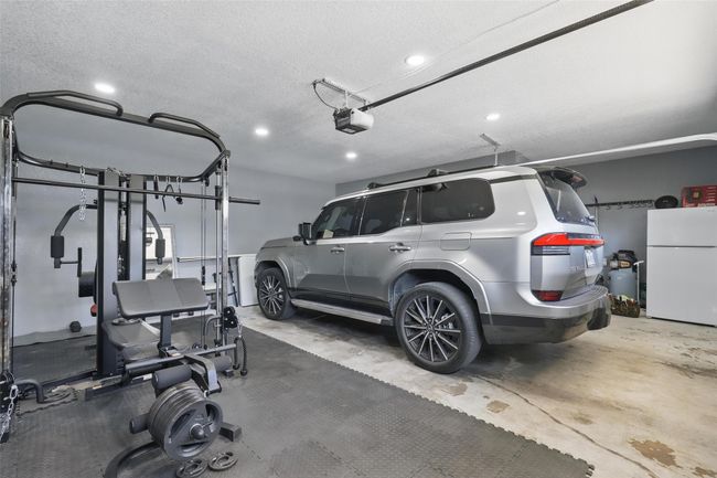 Garage featuring freestanding refrigerator, a garage door opener, and recessed lighting | Image 34