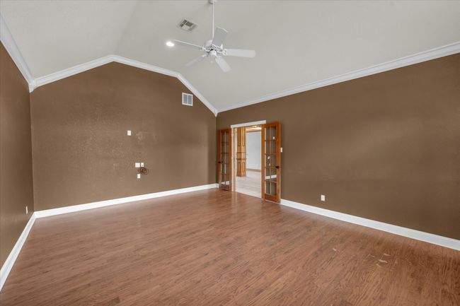 Empty room with lofted ceiling, french doors, a ceiling fan, crown molding, and wood finished floors | Image 32