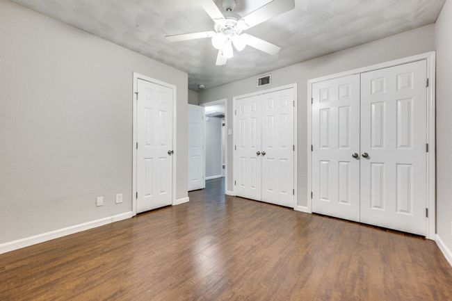Unfurnished bedroom featuring wood finished floors, multiple closets, and ceiling fan | Image 8