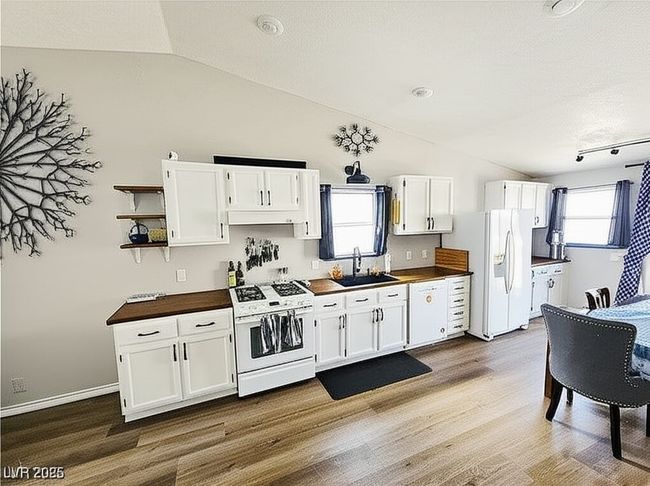 Kitchen with open shelves, white cabinets, white appliances, lofted ceiling, and light wood-style flooring | Image 6