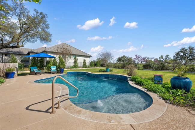 View of swimming pool featuring upgraded tile and waterfall. | Image 25