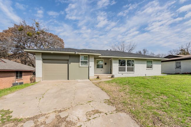 View of front facade featuring an attached garage, concrete driveway, a front yard, brick siding, and central AC | Image 34
