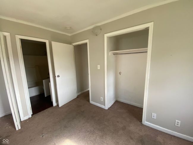 unfurnished bedroom featuring crown molding, a closet, carpet flooring, and baseboards | Image 10