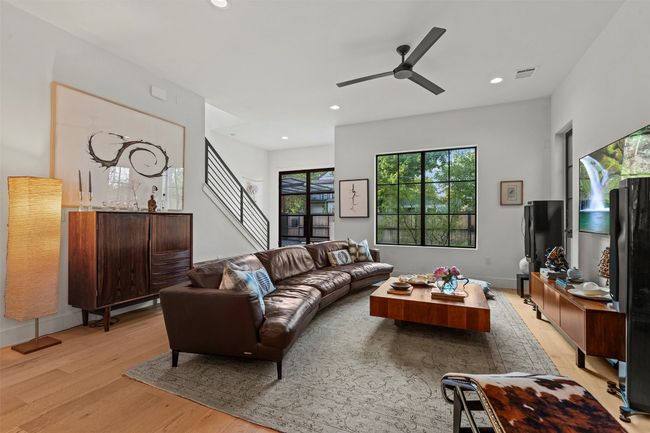 Living room featuring light wood finished floors, ceiling fan, stairway, and recessed lighting | Image 4