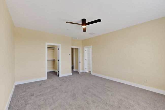 Unfurnished bedroom with carpet floors, a walk in closet, and a ceiling fan | Image 9