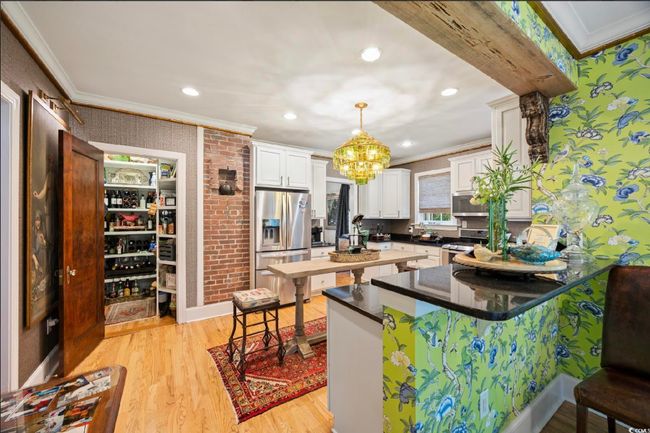 Kitchen with crown molding, stainless steel appliances, a peninsula, light wood-style floors, and white cabinetry | Image 25