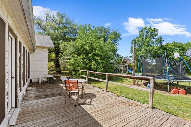 Wooden deck featuring a trampoline, a lawn, outdoor dining space, and a playground | Image 34