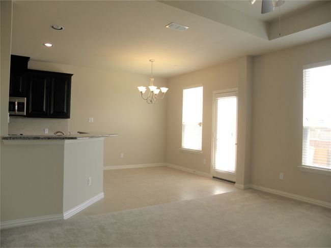 Kitchen featuring stainless steel microwave, dark cabinetry, light carpet, a ceiling fan, and a chandelier | Image 6