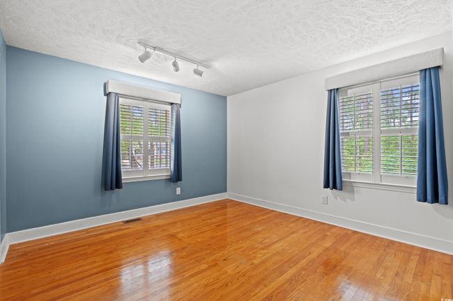 Unfurnished room featuring wood finished floors, a textured ceiling, track lighting, baseboards, and visible vents | Image 13