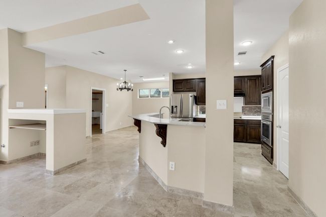 Kitchen featuring light countertops, visible vents, a spacious island, dark brown cabinetry, and appliances with stainless steel finishes | Image 16