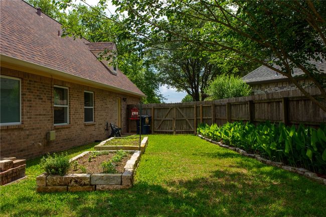 View of yard featuring a fenced backyard, a garden, and a gate | Image 38