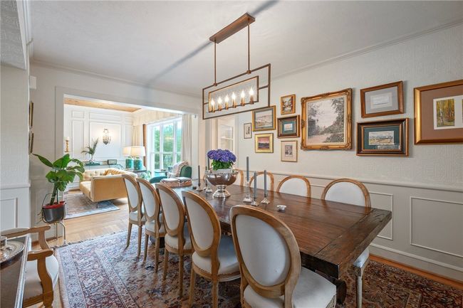 Dining area with a decorative wall, crown molding, wood finished floors, a chandelier, and a wainscoted wall | Image 8