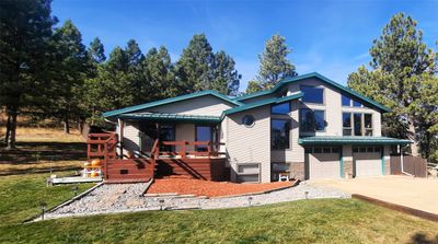 View of front of home featuring a front yard, a wooden deck, and a garage | Image 1