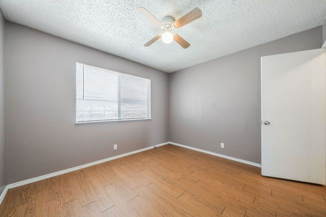 Empty room with a textured ceiling, ceiling fan, and wood finished floors | Image 28