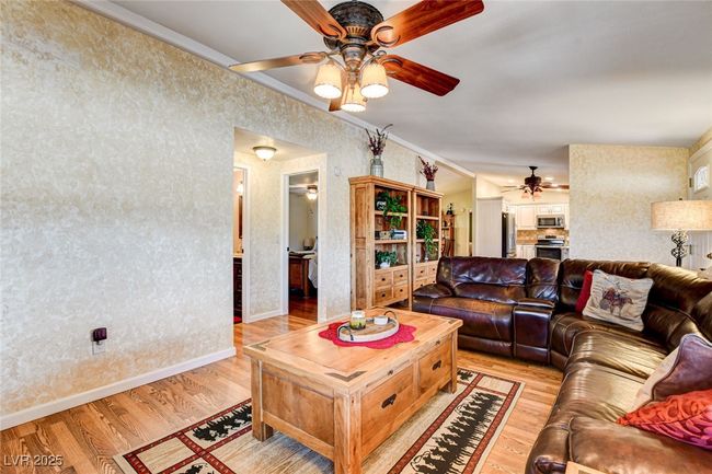 Living area with a ceiling fan, light wood-type flooring, and crown molding | Image 11