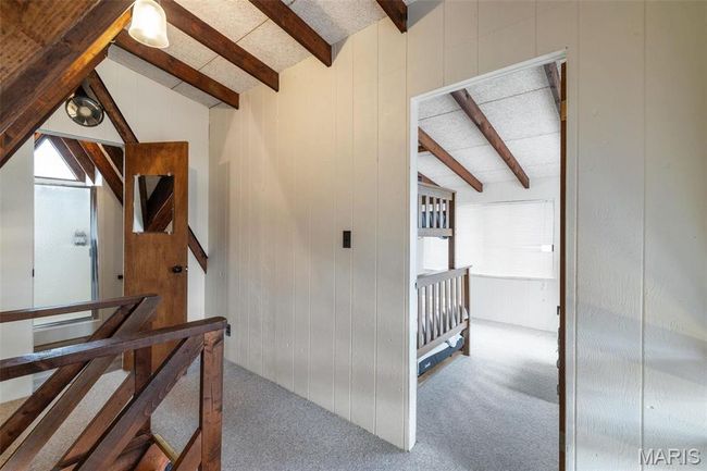 Stairway with lofted ceiling with beams, wood walls, and carpet floors | Image 33