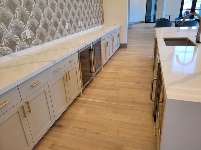 Kitchen featuring light wood-type flooring, beverage cooler, light stone counters, and a sink | Image 29