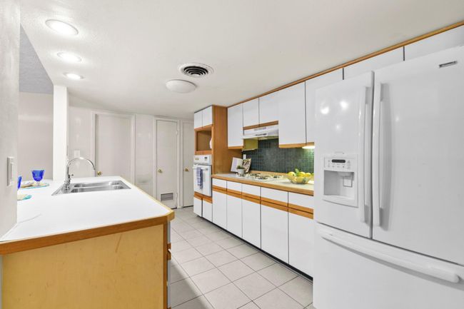 The kitchen features an island with a double sink and ample storage. | Image 10