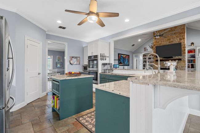Kitchen featuring green cabinets, a ceiling fan, a kitchen island, visible vents, and stainless steel appliances | Image 15