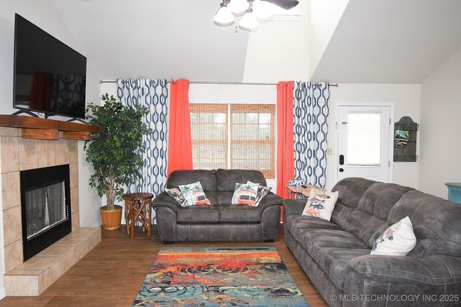 Living room featuring wood finished floors, lofted ceiling, and a tile fireplace | Image 7