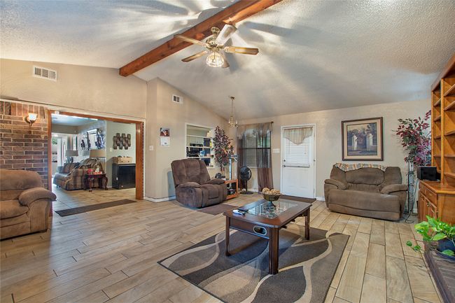Living area featuring ceiling fan, light wood-style floors, visible vents, and vaulted ceiling with beams | Image 5