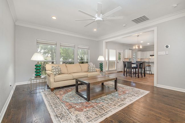 Den with ceiling fan, crown molding, hardwood floors, and recessed lighting, looks into breakfast room and kitchen | Image 11