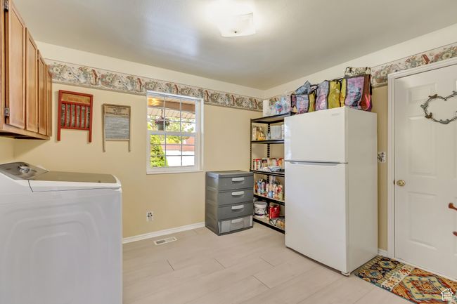 Washroom featuring washer / dryer, baseboards, visible vents, and cabinet space | Image 16