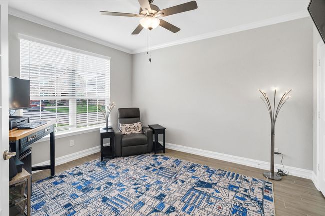 Office features crown molding, an oversized window and ceiling fan. | Image 6