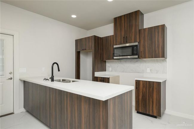 Kitchen with stainless steel microwave, modern cabinets, a sink, light marble finish floors, and recessed lighting | Image 7