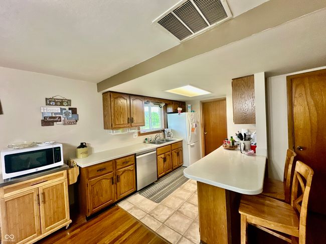 kitchen featuring white appliances, a sink, light countertops, and brown cabinets | Image 17
